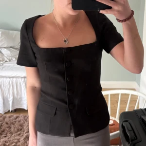 Svart kortärmad blus med knappar Zara - Snygg svart blus med korta ärmar och knappar framtill. Den har en fyrkantig urringning och figurnära. Jätte fin, ifrån Zara