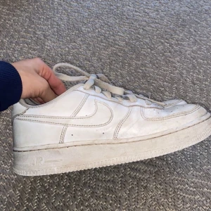 Vita Nike Air Force sneakers - Säljer ett par klassiska vita Nike Air Force sneakers. De har en ikonisk design med snörning och en robust sula. Perfekta för en stilren och sportig look.