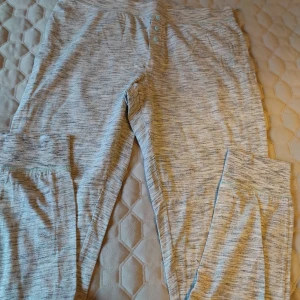 Grå pyjamas från H&M - Säljer ett par grå mjukisbyxor från H&M. Byxorna har en bekväm passform med knappar framtill och är tillverkade i ett mjukt material. Perfekta för en avslappnad dag hemma.
