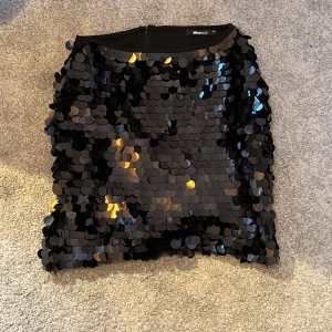 Svart paljettkjol från Gina Tricot - Snygg svart kortkjol från Gina Tricot täckt med glittrande paljetter. Perfekt för en kväll ute eller en festlig tillställning. Kjolen har en dragkedja baktill för enkel på- och avtagning. Gör ett statement med denna glittriga kjol! Använd en gång💕💕