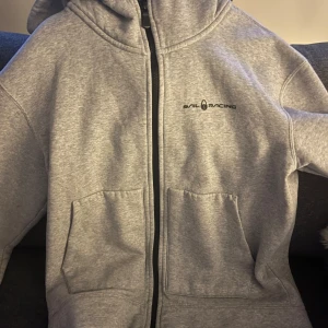 Grå hoodie från Sail Racing - Säljer en grå hoodie från Sail Racing med dragkedja och två praktiska fickor framtill. Nästan aldrig använd 