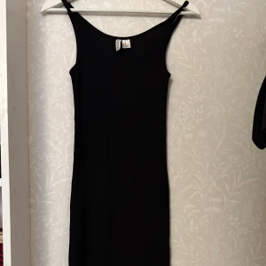 Svart klänning från H&M Divided - Säljer en stilren svart klänning från H&M Divided. Klänningen är ärmlös med smala axelband och har en tight passform. Perfekt för en minimalistisk look.