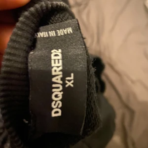 Svart tröja från Dsquared2 med tryck - Säljer en svart tröja från Dsquared2 med färgglada tryck och textdetaljer som 'AFTER LIFE!' och 'CANADUH!'. Tröjan har långa ärmar och en avslappnad passform. Perfekt för dig som gillar unika och uttrycksfulla plagg. Har krympt lite i tvären så är mer M eller S