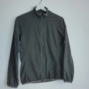 Grå fleecejacka från McKinley - Säljer en grå fleecejacka från McKinley med dragkedja framtill. Jackan har en enkel design med långa ärmar och är perfekt för kyligare dagar. Den är mjuk och bekväm, idealisk för utomhusaktiviteter.