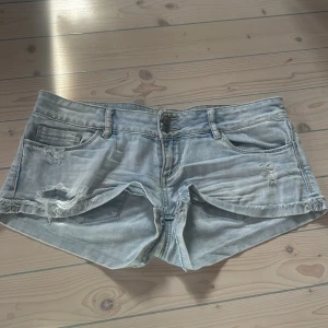 Ljusa jeansshorts med slitningar, LOW WAISTED! - Snygga ljusa jeansshorts med coola slitningar och fransiga kanter. Perfekta för en avslappnad sommarlook. De har en klassisk femficksdesign och knappgylf.
