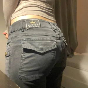 Grå byxor från IBER - Snygga grå byxor från IBER med låg midja och knappdetaljer. Plus ena fickan har förlorat knappen.