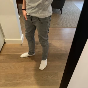 Grå jeans från Nudie Jeans - Snygga grå jeans från Nudie Jeans med slimfit passform. SJUKT snygga och bra pris. Han på bilden är 176 och de sitter riktigt najs😁