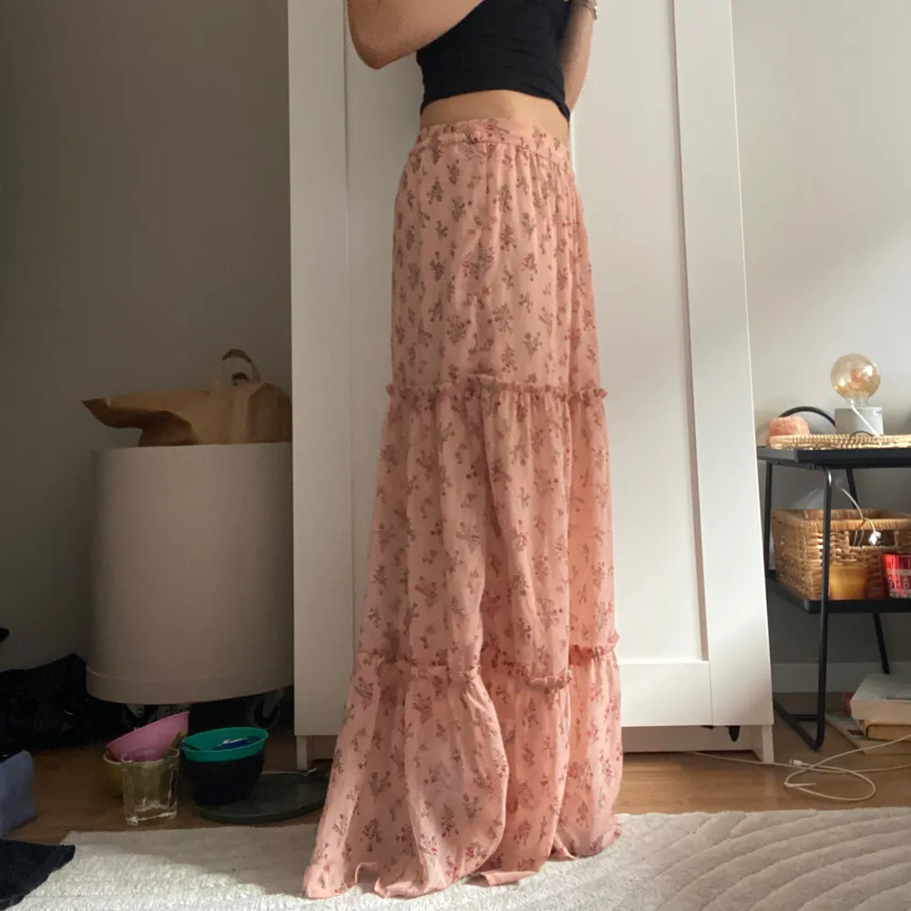 Säljer en rosa långkjol med blommigt mönster. Kjolen har volanger och är väldigt luftig. . Hameet.