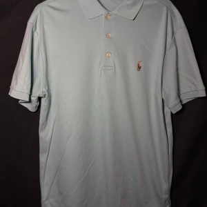 Ralph Lauren piké | Turkos/Ljusblå | Slim Fit | Stl M - Läs nedan för mer info!😊  Säljer en stilren ljusblå pikétröja från Ralph Lauren i slim fit. Tröjan har korta ärmar och en klassisk krage med tre knappar. Den ikoniska broderade logotypen syns på bröstet. Perfekt för en avslappnad men ändå elegant look.  Produktinformation:  ✅ Märke: Ralph Lauren  ✅ Storlek: M  ✅ Färg: Turkos ✅ Material: Bomull ✅ Passform: Slim fit – perfekt att styla med jeans eller chinos. ✅ Skick: Mycket bra skick, knappt använd  Frakt och betalning: 📦 Snabb leverans – skickar