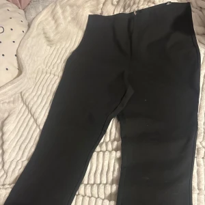 Svart byxa med dragkedja från H&M - Snygg svart byxa från H&M med dragkedja baktill. Perfekt för en stilren look. Byxan har en enkel design som gör den lätt att matcha med olika toppar.