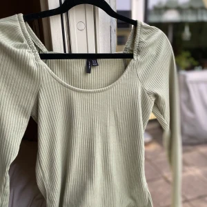 Ljusgrön ribbad topp från H&M - Säljer en ljusgrön ribbad topp från H&M med långa ärmar och rund halsringning. Perfekt för en stilren och bekväm look. Passar bra till både jeans och kjol.