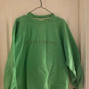 Grön sweatshirt från Acqua Limone - Säljer en grön sweatshirt från Acqua Limone med tryck på både fram- och baksidan. Tröjan har långa ärmar och en avslappnad passform. Perfekt för en casual look!