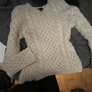 vit stickad tröja - Säljer en mysig vit stickad tröja med ett snyggt flätmönster. Tröjan har långa ärmar och ribbstickade muddar vid ärmslut och nederkant. Perfekt för höst eller vår dagar!!😛pm för frågor 💋