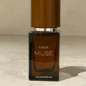 CAIA Muse Eau de Parfum - Elegant och stilren parfymflaska från CAIA med doften Muse. Flaskan är brun och rektangulär med en matchande brun kork. Perfekt för den som söker en sofistikerad och modern doft.