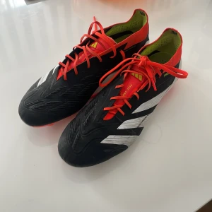 Adidas Predator Elite fotbollsskor - Säljer ett par Adidas Predator fotbollsskor i svart och röd med vita detaljer. Skorna är knappt använda och har fortfarande väldigt mycket användning kvar. Säljer dom då jag inte har någon användning för de.