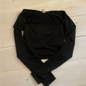 Svart offshoulder topp från Nelly - Snygg svart offshoulder topp från Nelly. Perfekt för en stilren look med långa ärmar och en tight passform. Enkel att matcha med olika outfits.