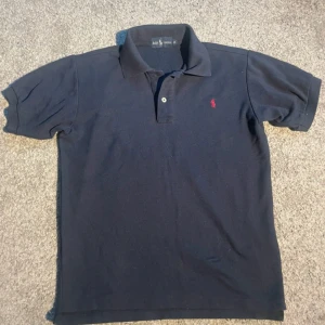 Ralph lauren piké  - En fet piké från Ralph lauren. Den är i toppskick men översta knappen saknas, man brukar inte ha den knäppt. 149kr🙂