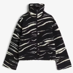 Svart och vit teddyjacka med zebramönster - Säljer en mysig teddyjacka i svart och vitt med zebramönster. Jackan har en dragkedja framtill och hög krage. Ser precis ut som på bilden, använd ca 2 gr🥰