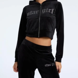 Svart velour hoodie med dragkedja - Snygg svart velour hoodie med texten 'star girl' på bröstet. Den är croppad och har en dragkedja framtill. Perfekt för en avslappnad stil och har en matchande mellan midjan utsvängd mjukis byxor till från new yorker.