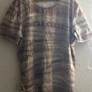 Beige t-shirt med textmönster - Säljer en beige t-shirt med ett unikt textmönster i olika färger. T-shirten har korta ärmar och en avslappnad passform. Perfekt för en casual look.