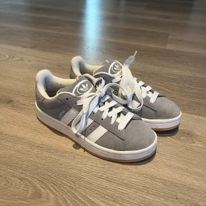 Grå Adidas campus 00 sneakers - Snygga grå Adidas campus 00 sneakers i mocka med vita detaljer och snörning. De är i väldigt bra skick och nypris är 1500kr💖