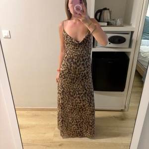 Leopardmönstrad långklänning - Säljer en snygg leopardmönstrad långklänning med smala axelband. Klänningen har en avslappnad passform och är perfekt för en trendig look. 🐆