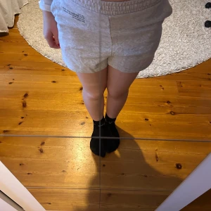 Grå mjukisshorts - Säljer ett par bekväma grå mjukisshorts med elastisk midja och tryckdetalj på framsidan. Perfekta för en avslappnad dag hemma eller lätt träning. De har en lös passform och är gjorda i mjukt bomullsmaterial.