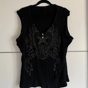 Svart ärmlös topp från Soyaconcept - Snygg svart ärmlös topp från Soyaconcept med ett coolt stjärnmönster i silverfärgade nitar på framsidan. Toppen har en v-ringning och är perfekt för en trendig look.