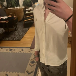 Vit skjorta från Ralph Lauren - Säljer en stilren vit skjorta från Ralph Lauren. Skjortan är perfekt för sommarn och funkar även att ha under tröjor. Den är i linne och riktig skön. Säljer då den växt ur