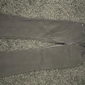 Svarta bootcut jeans - Snygga svarta bootcut jeans med knappar i midjan. Midjemått är 31 och längden 32. 