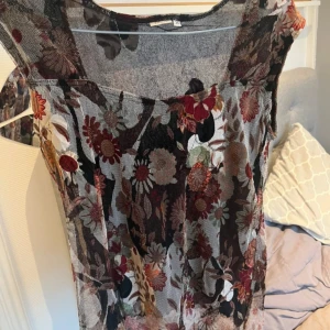 Blommig blus från Tess - Säljer en blommig blus från Tess i storlek 36. Blusen har ett färgglatt mönster med blommor i rött, brunt och beige🩷