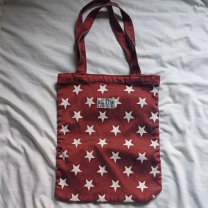 Totebag från converse - Säljer en cool röd shoppingväska från Converse med vita stjärnor över hela ytan. Väskan är tillverkad i 100% bomull. 