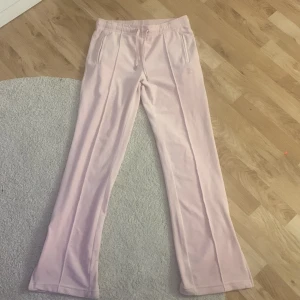 Rosa mjukisbyxor från Juicy Couture - Säljer ett par ljusrosa mjukisbyxor från Juicy Couture med elastisk midja. Byxorna har också en liten fläck på sig men syns knappt. Snygga och bekväma 