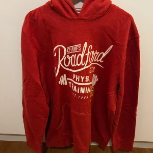 Röd hoodie från F&F - Säljer en röd hoodie från F&F med tryck på framsidan. Perfekt för träning eller en avslappnad dag. Den har en klassisk känguruficka och en bekväm huva.
