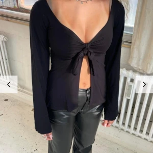 Svart långärmad topp med knyt - Snygg svart långärmad topp med v-ringning och knyt framtill. Perfekt för en mer festligare look ,väldigt liten i storlek säljer Pgr av att den är förliten storleken är xs/S men känns mer som en xxs/Xs knappt använd .Kan även byta mot en storlek större 🥰.köp via plick ❤️