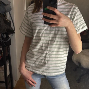Randig t-shirt - Säljer en randig t-shirt i vitt och ljusgrönt. T-shirten har medellängd ärmar och en normal passform. Perfekt för en varm sommar dag! Hör av dig vid intresse💕