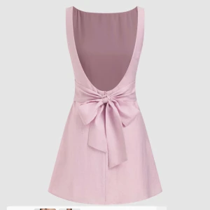 Klänning Rosa med rosette  - Jättefin rosa klänning med rosette och öppen rygg! Materialet är som linne plus något inre tyglager. Skön och kort! Aldrig använd! Lappen kvar på! Alltså nyskick🩷