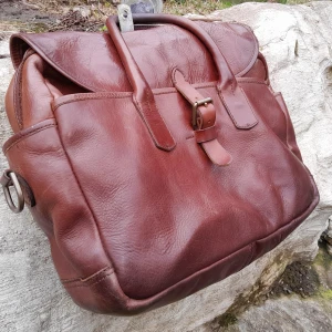 Ralph Lauren Vintage skinnväska  - Säljer en snygg brun Vintage Ralph Lauren skinnväska med ett klassiskt spänne framtill. Väskan har två handtag och en rymlig insida med dragkedja. Perfekt för dig som gillar stil och funktionalitet.