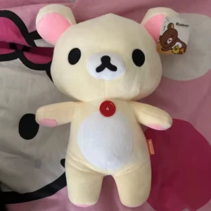 Sista dagen fri frakt! Kramdjur Korilakkuma från Rilakkuma - Säljer ett gulligt kramdjur föreställande Kiiroitori från Rilakkuma-serien. Den är ljusbeige med vita detaljer och har en röd knapp på magen. Perfekt för alla som älskar söta och mjuka gosedjur! 🐻 Ny! Mått ca 27cm.