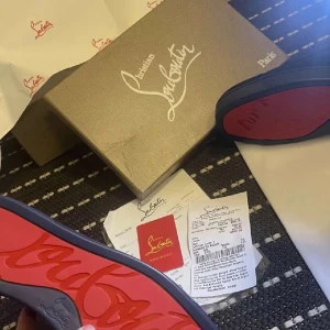 Svarta sneakers från Christian Louboutin - Snygga svarta sneakers från Christian Louboutin med den ikoniska röda sulan. Skorna har en stilren design med snörning och är perfekta för att ge en lyxig touch till din outfit. 1960kr