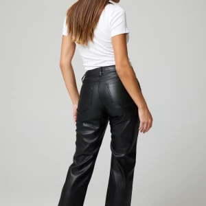 Svarta skinnbyxor - Snygga svarta skinnbyxor med hög midja och rak passform. Byxorna har en stilren design med fickor både fram och bak, vilket ger en cool look. Perfekta för att ge din outfit en edgy touch.