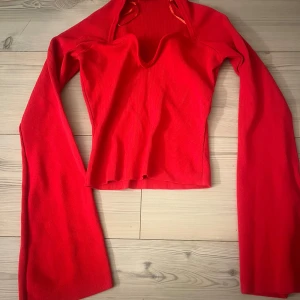 Röd ribbad tröja - Säljer en snygg röd ribbad tröja med lång ärm och en unik v-ringad design. Perfekt för att sticka ut med sin starka färg och stilrena look. Passar bra till både jeans och kjol. Och har utsvängda armar! Sitter jätte snyggt 💕använd två ggr