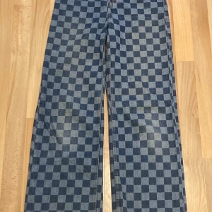 Rutiga jeans med hög midja - Högmidjade jeans med ett rutigt mönster i blått. Byxorna har wide legs och är justerbara i midjan. De är lite slitna längst ner på benen, men inget mycket. Vid bakfickorna så kan man se tecken på andvändning där de är lite mer slitna, men inget man tänker på.💕