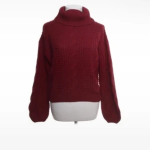 Vinröd stickad polotröja från Don't Call Me Jennyfer - Säljer en mysig vinröd stickad polotröja från Don't Call Me Jennyfer. Tröjan har ett klassiskt flätmönster och långa ärmar, perfekt för kyliga dagar. Den är tillverkad i 100% akryl och har en hög polokrage som håller dig varm. Perfekt för höst och vinter! 🍂❄️