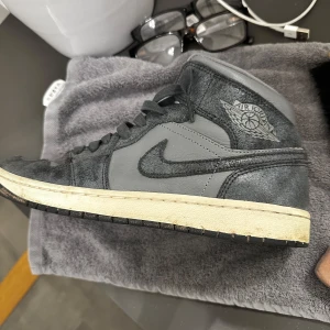 Grå Nike Air Jordans - Säljer ett par grå Nike Air Jordans med svart snörning och en klassisk design. Skorna har en kombination av skinn och mocka vilket ger dem en stilren look. Perfekta för sneaker-entusiaster!