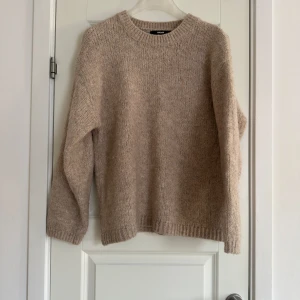 Beige stickad tröja från Bikbok - Mysig beige stickad tröja från Bikbok med rund hals och långa ärmar. Perfekt för kyliga dagar och enkel att matcha med olika outfits.