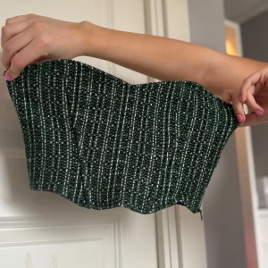 Grön och vit randig tubtopp - Snygg grön tubtopp med vita ränder. Perfekt för en stilren look. Toppen är axelbandslös och har en bekväm passform.