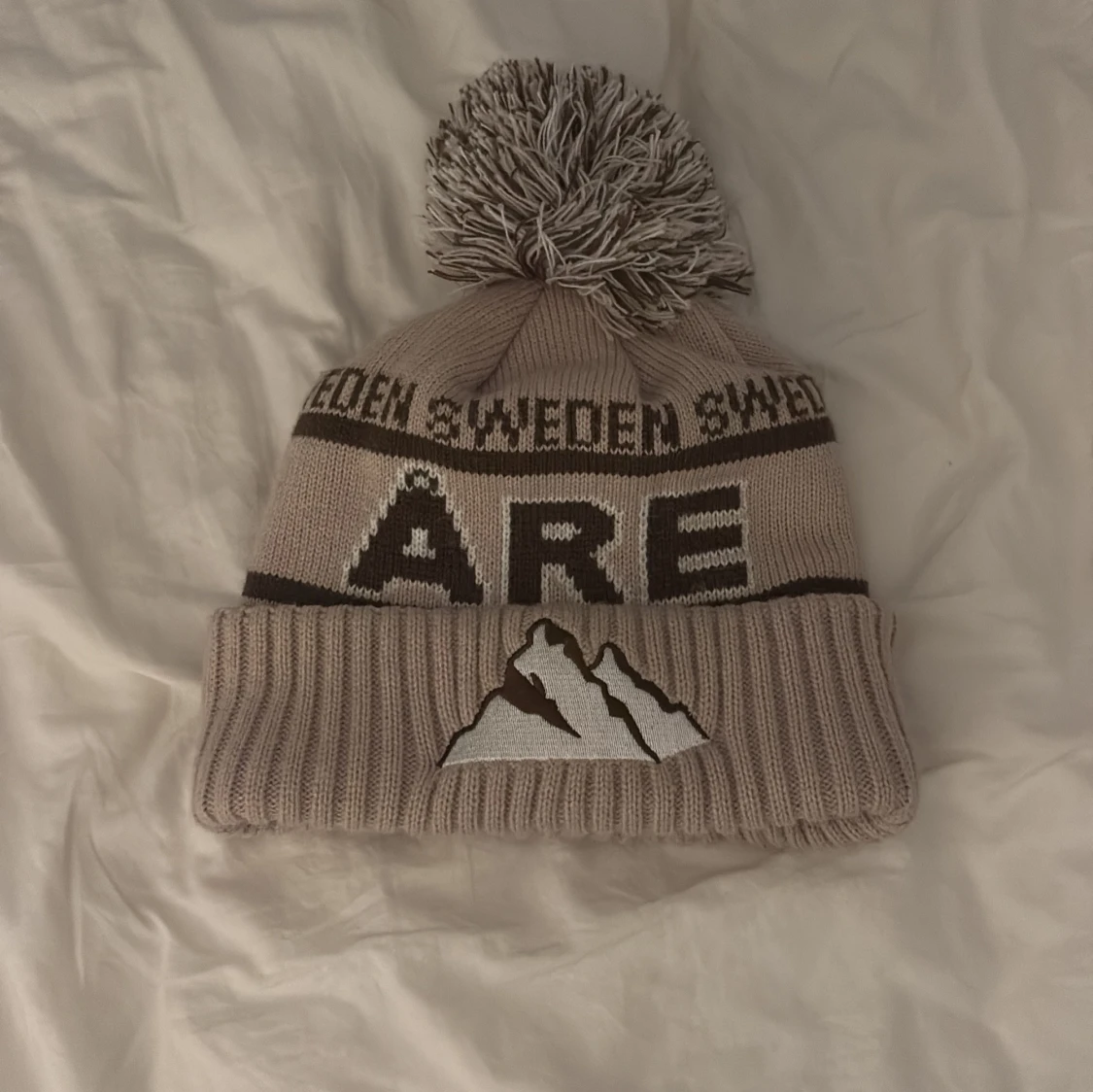 Beige mössa med tofs från Åre 