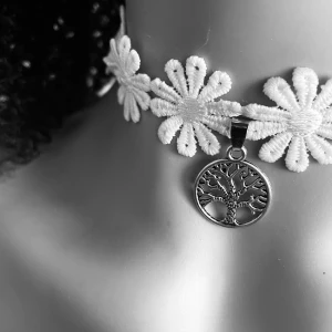 By prisförslag- Vit blomchoker med livets träd-hänge - Charmig choker med vita blommor och ett silverfärgat hänge föreställande livets träd. Blommorna har gula mittpunkter som ger en fin kontrast. Perfekt för att ge en bohemisk touch till din stil.