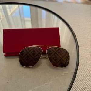 Fendi Solglasögon  - Unisex Fabulous oversize aviator solglasögon från FENDI. Guldfärgad metall, brun linser med FF-logotyp och guld överallt.